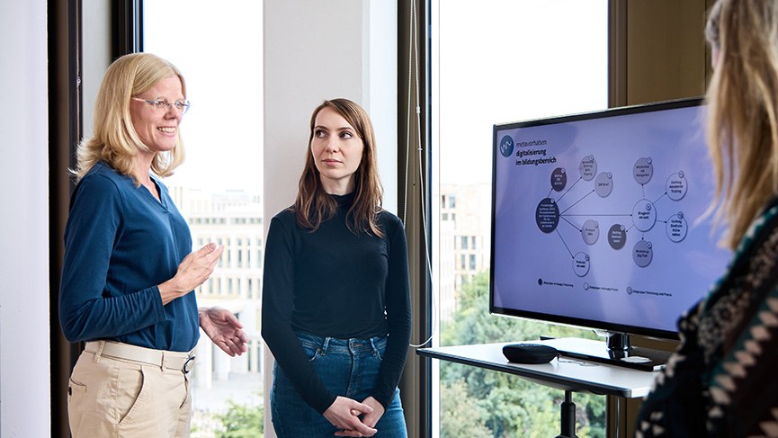 Forschungssynthesen: Evidenzbasierte Wissenschaft stärken Schmuckbild: Personen diskutieren über Präsentation